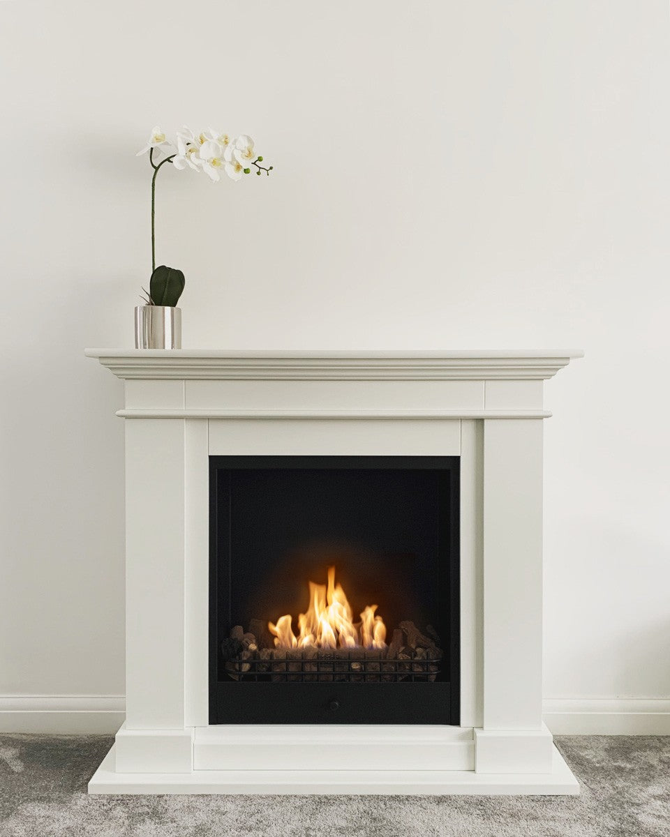 Roma Traditional Bioethanol Fireplace with Orchid on top against white wall 