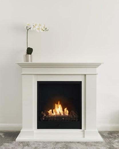 Roma Traditional Bioethanol Fireplace with Orchid on top against white wall 