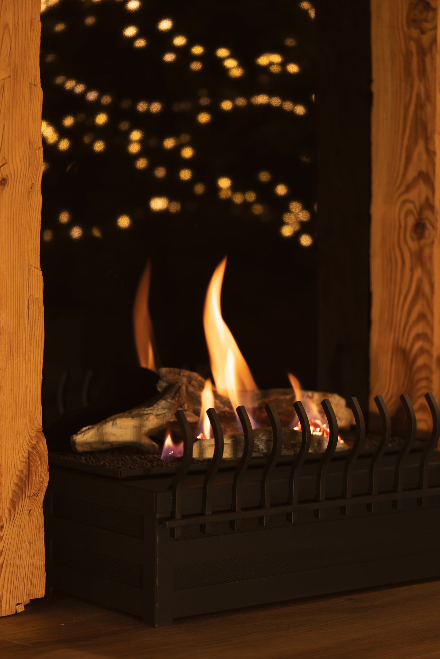 Planika Basket Fire with logs, frontal grate and wooden mantelpiece. Close up picture.