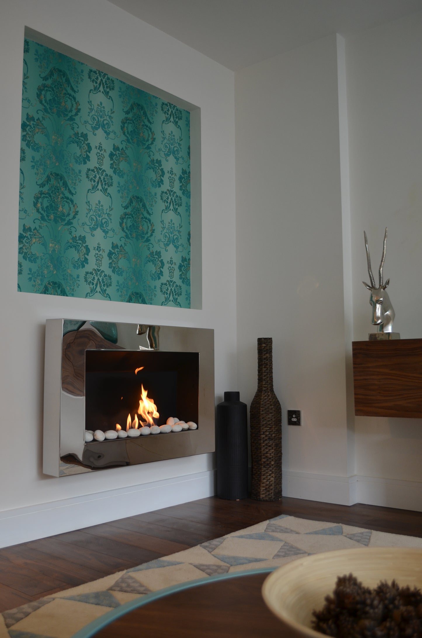 Phantom mirrored fireplace with white pebbles on decorative wall . Side view