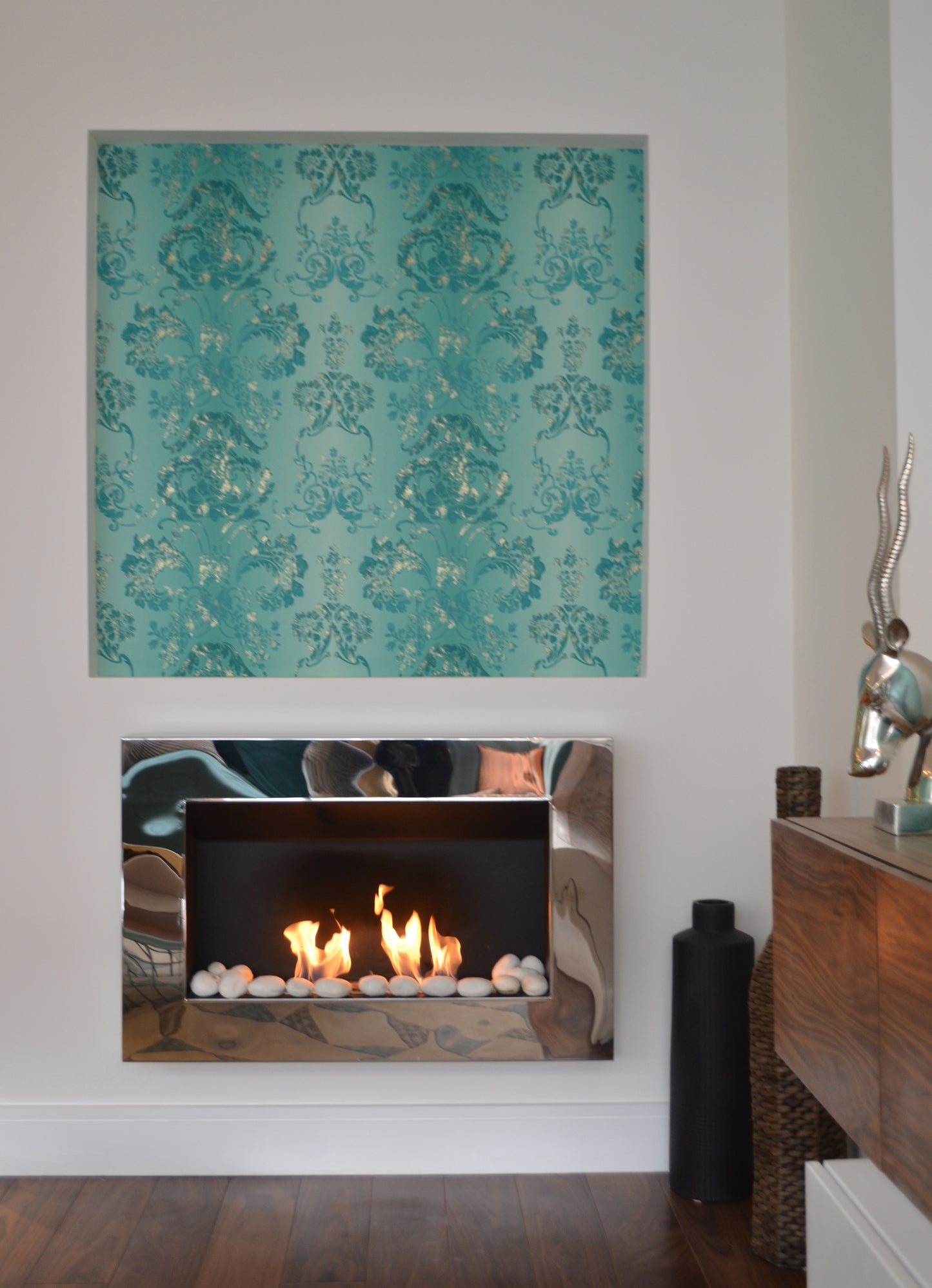 Phantom mirrored fireplace with white pebbles on decorative wall . Front view