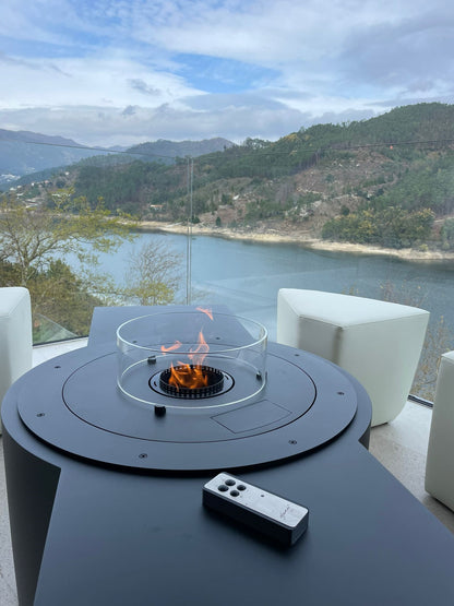 Circus with automated bioethanol burner and white ottomans. Close up on the remote control and panoramic view on the river in the background