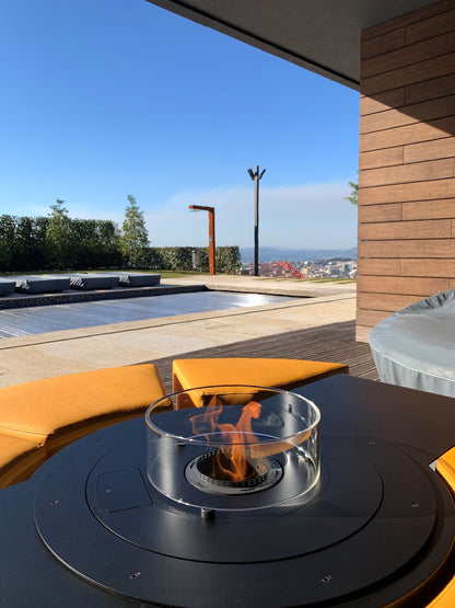 Circus with automated bioethanol burner and saffron yellow ottomans on semi-covered patio with swimming pool. Close up picture on the flame.