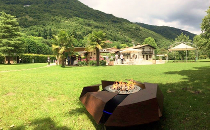 Stravaganza firepit with gas burner in rusted corten steel finish in  huge country house garden. Italy