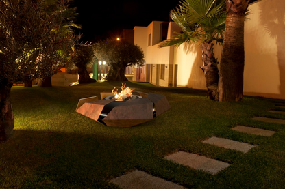 Stravaganza with woodburner in rusted corten steel finish in palm tree garden.